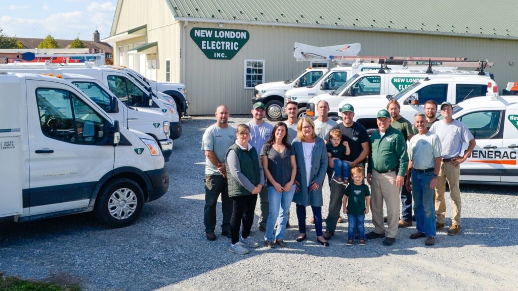 The New London Electric Team posing with their work vans in front of their main office