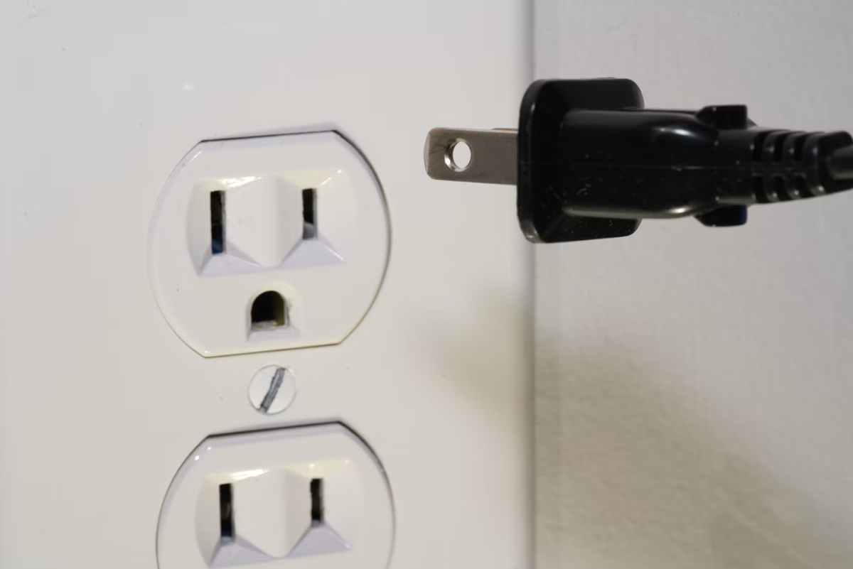 black cord being plugged into an electrical outlet.